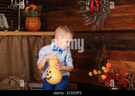 Niedlicher kleiner Junge mit Spaß in Halloween-Dekorationen. Halloween-Party mit Kind hält bemalten Kürbis Stockfoto