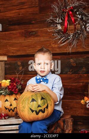 Halloween-Party mit Kind hält bemalten Kürbis. Niedlicher kleiner Junge mit Spaß in Halloween-Dekorationen Stockfoto