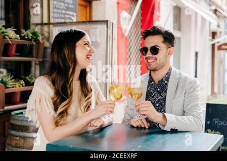 Stilvolles junges Paar mit Getränken, die im Café draußen auf der Straße sitzen und sich entspannen. Stockfoto