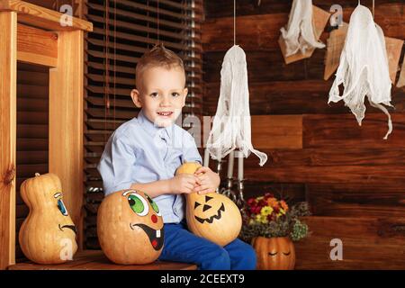 Halloween-Party mit Kind hält bemalten Kürbis. Kleiner Junge mit Spaß in Halloween-Dekorationen Stockfoto