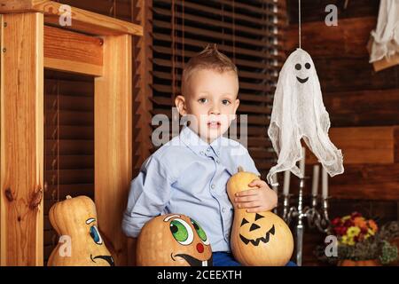 Halloween-Party mit Kind hält bemalten Kürbis. Niedlicher kleiner Junge mit Spaß in Halloween-Dekorationen Stockfoto