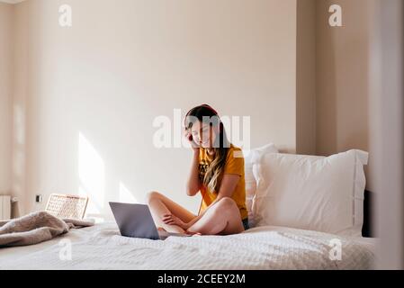 Fröhliche Frau in Kopfhörern mit Laptop Stockfoto
