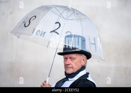 London, Großbritannien. September 2020. Extinction Rebellion proteste , in Zylinderhut, hält einen Regenschirm mit Anti HS2 Schrift auf der Seite. Rebellen versammeln sich auf dem Trafalgar Square, bevor sie zu den Häusern des parlaments marschieren. Frustriert über das Versagen der Regierung, auf die Klima- und ökologische Notlage zu reagieren, protestiert XR weiterhin für den Wandel. Der Climate and Ecological Emergency Bill (CEE Bill) ist der einzige konkrete Plan, der zur Verfügung steht, um diese Krise zu bewältigen, und so fordert XR an ihrem ersten Tag im Parlament die Regierung, jetzt zu handeln und diese Gesetzgebung anzunehmen. Quelle: Neil Atkinson/Alamy Live News. Stockfoto