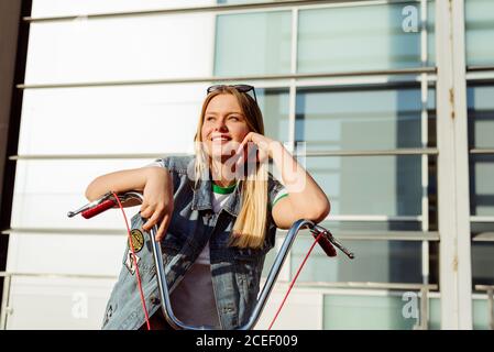Attraktive junge Frau, die auf einem Oldtimer-Fahrrad sitzt Stockfoto