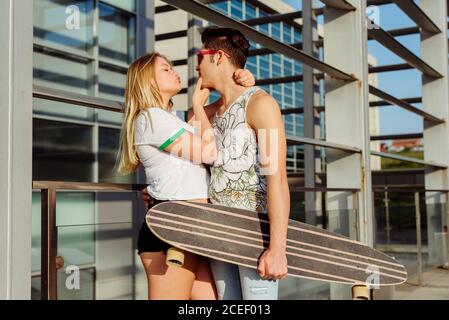 Junges Paar, das Hände hält und Skateboard trägt Stockfoto