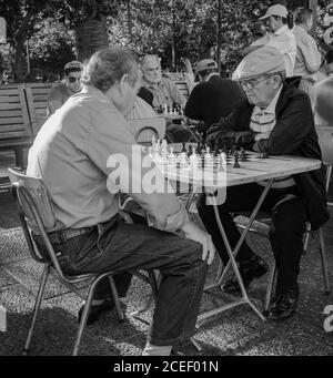 SANTIAGO, CHILE - Dec 23, 2017: Zwei ältere Männer spielen Schach im Freien auf einem Platz, der von anderen Schachspielern umgeben ist. Santiago, Chile Stockfoto