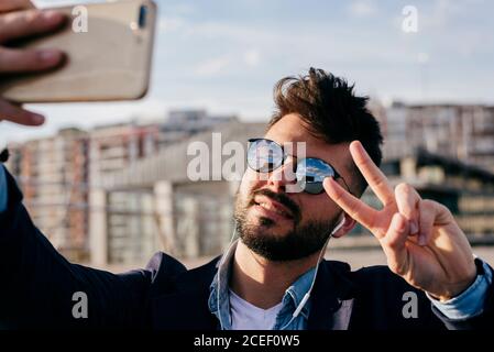 Lächelnder, trendiger Mann, der Selfie nimmt Stockfoto