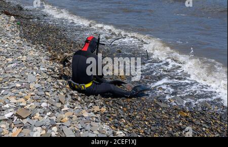 Taucher sitzt am Ufer und bereitet sich auf das Tauchen vor. Stockfoto