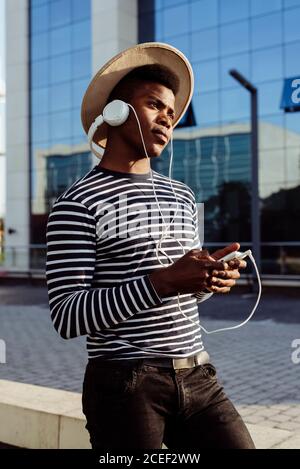 Schwarzer Mann in Kopfhörer mit Smartphone Stockfoto