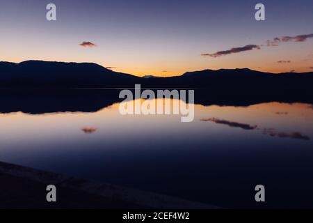 Malerische Ansicht von wunderbaren Sonnenuntergang Himmel über Bergrücken und ruhigen Wasser Stockfoto