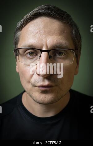 Porträt eines ernsten 40-jährigen weißen (kaukasischen) Mannes mit Brille. Rembrant Beleuchtung. Stockfoto