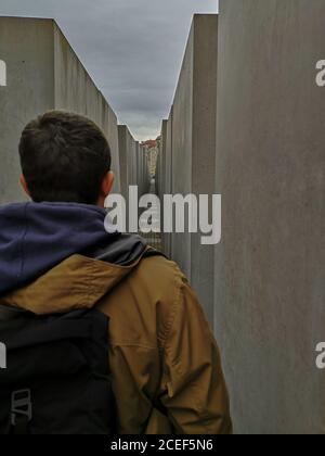 Mann, der allein durch graue Betonstelen im Holocaust-Mahnmal für die während des Zweiten Weltkriegs ermordeten juden geht. Stockfoto