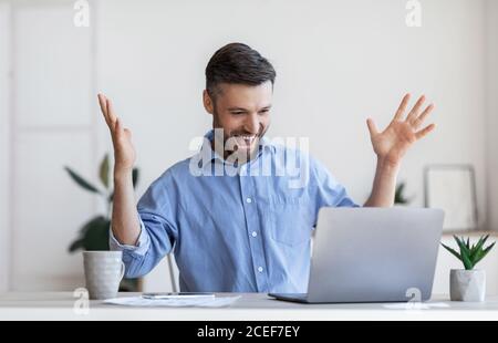 Glückliche männliche Unternehmer emotional feiert Geschäftserfolg mit Laptop in Büro Stockfoto