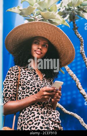 Frau mit einem Strohhut zu Fuß in einer schönen Architektur Sprechen auf dem Handy Stockfoto
