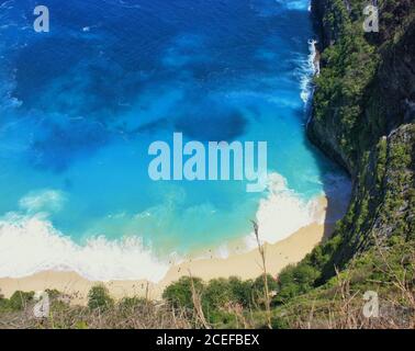 Tiefblaues und türkisfarbenes Wasser unter dem Kelingking Beach, dem Boden der T-Rex Cliffs, in Nusa Penida, Indonesien Stockfoto