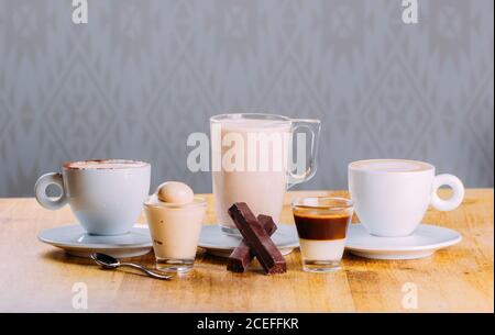 Anordnung von Tassen auf Untertassen mit verschiedenen Heißgetränken und Köstliche süße Desserts im Sortiment Stockfoto