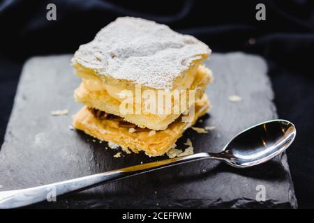 Nahaufnahme des servierten Dessert aus Blätterteig und verschiedenen Cremes mit Zuckerpulver. Stockfoto