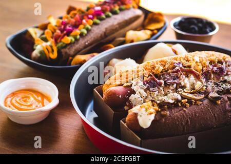 Serviert Snacks mit Hot Dog gekrönt mit leckeren und kreativen Zutaten. Stockfoto