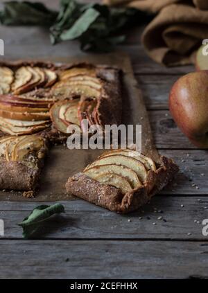 Totes Blatt und reifer Apfel liegen in der Nähe schmackhafte Kuchen auf Tischplatte aus Holz Stockfoto