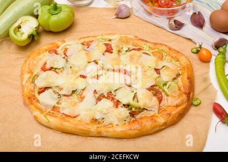 Hausgemachte vegane Pizza mit Zucchini, Tomaten, Paprika, Mozzarella auf einem hellen Hintergrund. Zutaten frisches Gemüse für Pizza . Draufsicht. Stockfoto