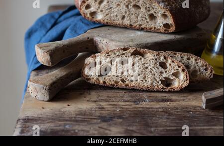 Stücke von frischem Vollkornbrot Kamut mit Dinkel und Bier auf Holzplatte liegend Stockfoto