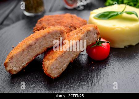 Cutlet mit gekochten Kartoffeln auf einem schwarzen Teller Stockfoto