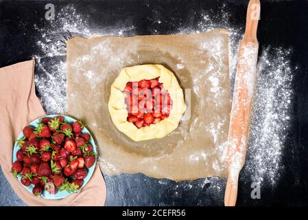 Schritt für Schritt Rezept der Prozess der Herstellung von Galetta mit Erdbeeren zu Hause, Draufsicht auf einem dunklen Hintergrund, Zutaten für Erdbeerkuchen. Stockfoto