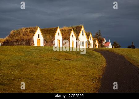 Es gibt ein paar Häuser mit Strohhäppchen, die Schlange stehen Feld in fröhlichen Tag in Island Stockfoto