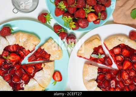 Hausgemachte Erdbeere Galette mit frischen reifen Erdbeeren auf einem hellen Hintergrund, Draufsicht. Zutaten in den Prozess der Herstellung Galetta. Stockfoto