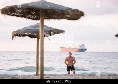 Starker alter Mann, der am Strand posiert. Stockfoto