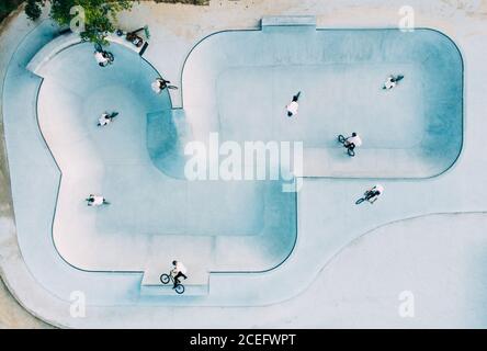 Von oben Blick auf geräumige Skate-Park mit Gruppe von Männer in weißen T-Shirts machen Tricks auf BMX Stockfoto
