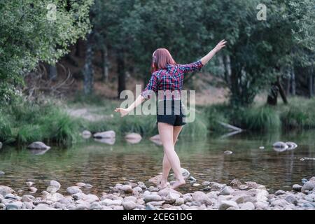 Ziemlich rothaarige Mädchen führt Übungen durch den Fluss. Stockfoto