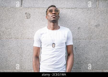 Afrikanischer Mann trägt weißes Hemd und Sonnenbrille posiert. Stockfoto