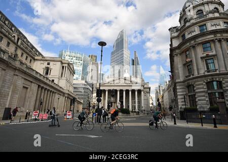 Radfahrer überqueren eine ruhige Bank Junction in der Nähe der Bank of England in der City of London. Der Premierminister sagte, dass die Leute "in großer Zahl ins Büro zurückkehren" würden, aber Downing Street sagte, dass sie noch keine Informationen zur Sicherung der Behauptung liefern könne. Stockfoto