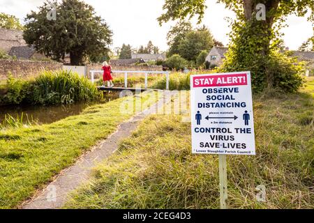 Stay Alert - Observe Social Distancing - Covid 19 Bekanntmachung errichtet vom gemeinderat in der Cotswold Dorf Lower Slaughter, Gloucestershire UK Stockfoto