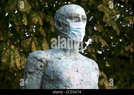 Ein Detail der Dorset Martyrs Skulptur von Dame Elizabeth Frink, zeigt eine Statue mit einer chirurgischen Gesichtsmaske während der Covid 19 Pandemie. England. Stockfoto