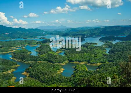 TA Dung See im Sommer. Blauer Himmel und Wolken auf dem See und die Bäume auf der kleinen Insel Paradies. Dak Nong globaler geologischer Park, Dak Nong Prov Stockfoto