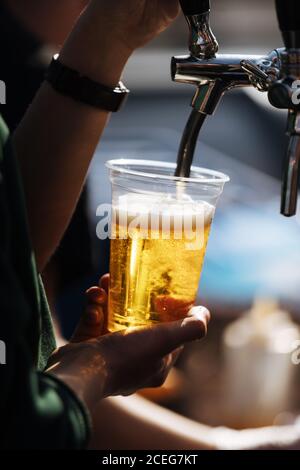 Ernte Schuss Server Gießen frisches Bier vom Fass in Plastikmüll im Restaurant Stockfoto