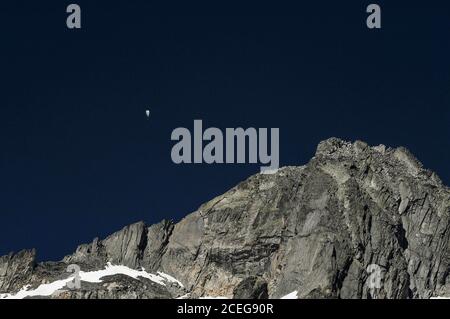 Ein eingleisiger Gleitschirm fährt in einem tiefblauen Himmel über einem schroffen Bergrücken der Urner Alpen hoch über dem 7.65 km (4.75 mi) Rhône Gletscher im Kanton Wallis, Schweiz. Das Schmelzwasser des Gletschers stürzt sich in ein tiefes Talbecken weit unten, um die 813 km (505 Meilen) lange Reise des Flusses Rhône zum Mittelmeer über Südfrankreich und das Camargue-Delta zu beginnen. Stockfoto