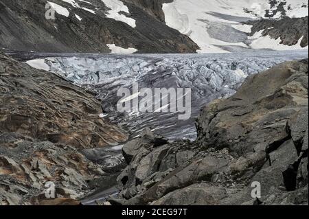 Der tief zerklüftete Rhône-Gletscher fließt auf etwa 30 bis 40 m (100 bis 130 ft) pro Jahr von Schneefeldern an den Hängen des 3,383 m (11,099 ft) Tieralplistocks bis zu einem Punkt unterhalb des Furka-Passes im Kanton Wallis, Schweiz, Wo das Eis in einem grünen See auf einer Höhe von etwa 2,208 m (7,244 ft) schmilzt. Das Schmelzwasser donnert tief unten in das Talbecken und beginnt die 813 km (505 Meilen) lange Reise des Flusses Rhône zum Mittelmeer über Südfrankreich und das Camargue-Delta. Stockfoto