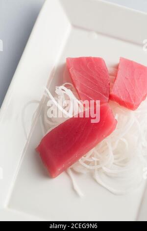 Traditionelle japanische Küche mit Scheiben rohen Fischs und geschreddert Radieschen auf weißem Hintergrund Stockfoto