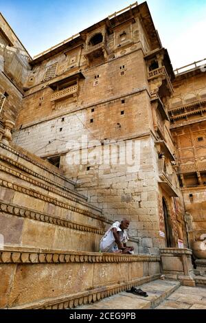 Jaisalmer, Indien - August 2020: Ein Mann sitzt am Eingang zum Palast von Jaisalmer Fort am 20. August 2020 in Jaisalmer, Rajasthan, Indien. Stockfoto