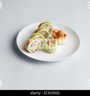 Helle leckere japanische Sushi-Brötchen mit Lachs in fliegenden Fischen Kaviar wunderschön auf weißem Teller auf weißem Hintergrund von gesetzt Oben Stockfoto