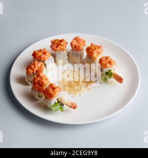 Helle leckere japanische Sushi-Brötchen mit Lachs in fliegenden Fischen Kaviar wunderschön auf weißem Teller auf weißem Hintergrund von gesetzt Oben Stockfoto