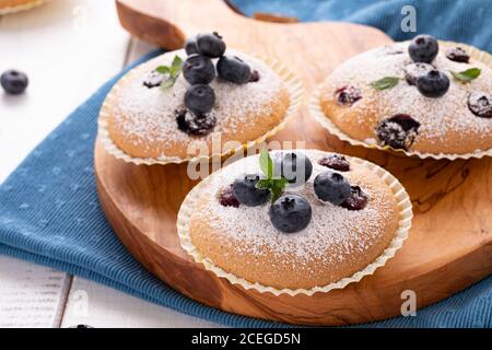 Nahaufnahme von Blaubeer Muffins auf Holzbrett und blaue Küche Serviette Stockfoto