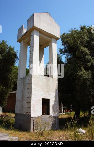 Hoher weißer Kontrollturm mit Leitern im Bau in einem Waldlichtung zwischen den Häusern im italienischen Tageslicht Stockfoto