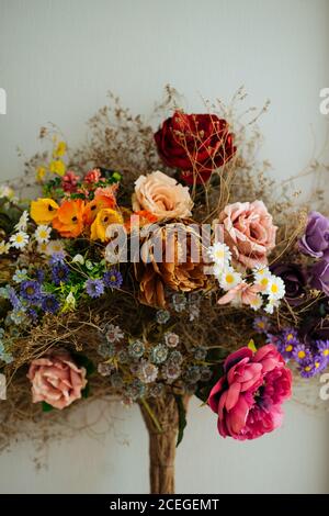 Elegante auffällige frische Rosen und Wildblumen mit schönen getrockneten gepflückt Blumen und Kräuter mit schwarzer Kordel auf grau gebunden Hintergrund Stockfoto