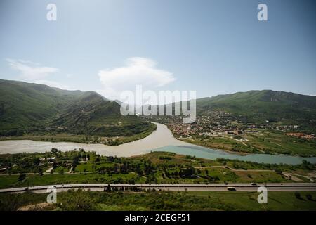 Panoramablick auf grüne Berge rund um die Altstadt und Fluss Zusammenfluss mit Straße in der Nähe an sonnigen Sommertag Stockfoto