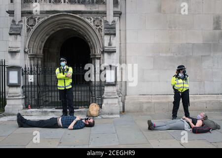 Die Polizei steht neben den verhafteten Demonstranten während einer Demonstration der Rebellion zum Aussterben im Zentrum von London. Die Umweltkampagnengruppe hat für Märsche an mehreren Sehenswürdigkeiten in der Hauptstadt geplant, bevor sie zum Parliament Square in Westminster umzieht. Stockfoto