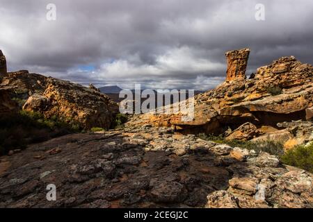 Sonnenlicht beleuchtet die Sandsteinsäule in den Cederberg Bergen, Südafrika, mit sich aufziehenden Sturmwolken im Hintergrund Stockfoto